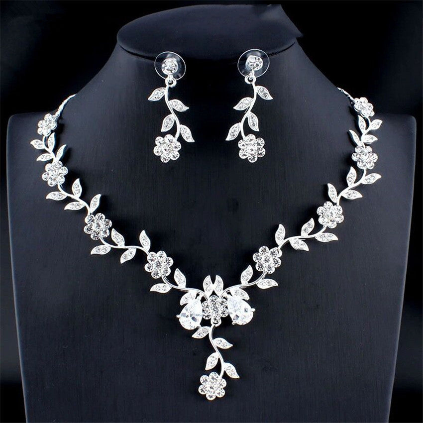 Silver floral necklace and earrings on a black stand