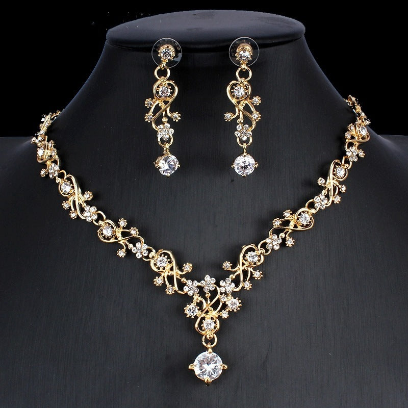 Gold necklace and earrings set on a black mannequin