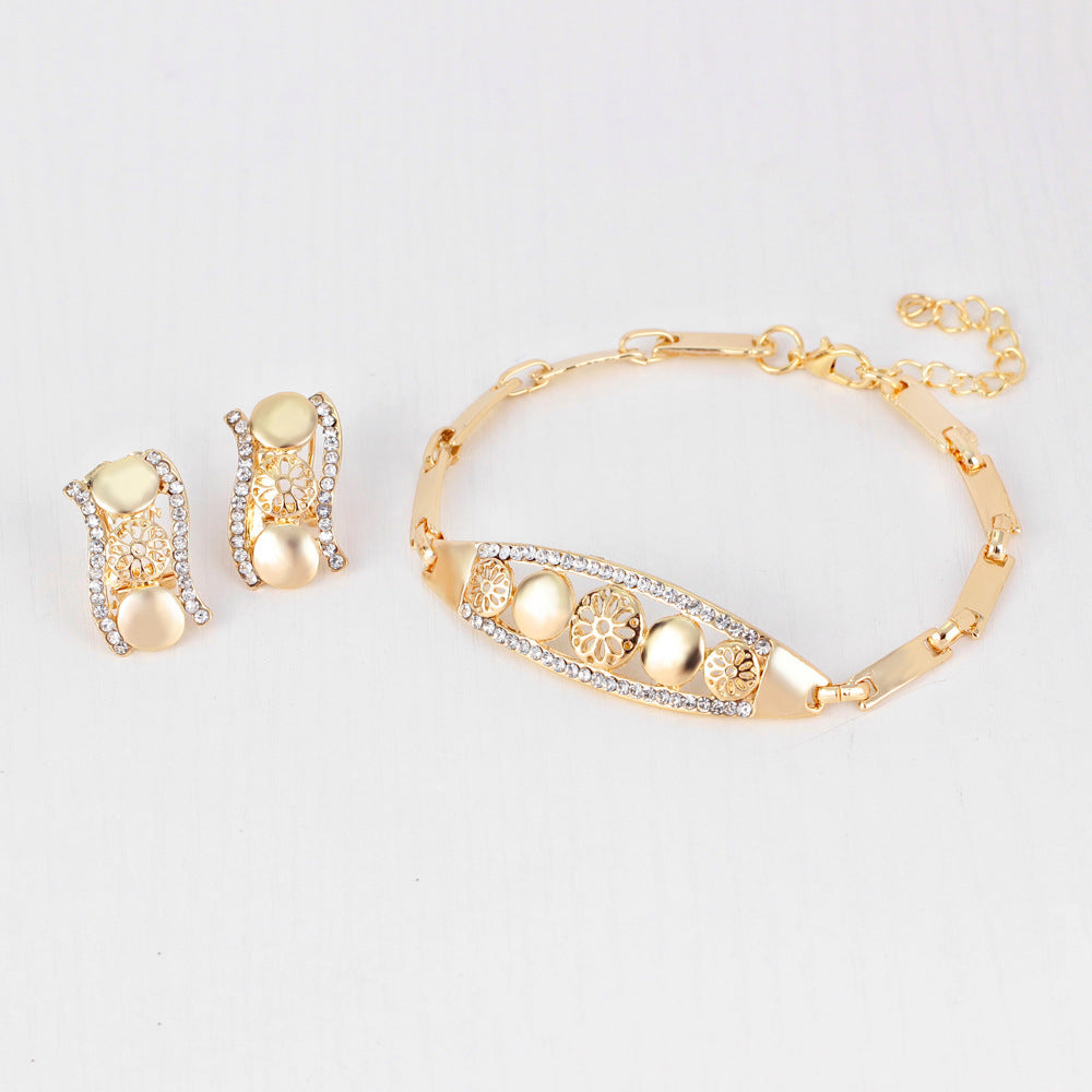 Gold bracelet and earrings on a light gray background